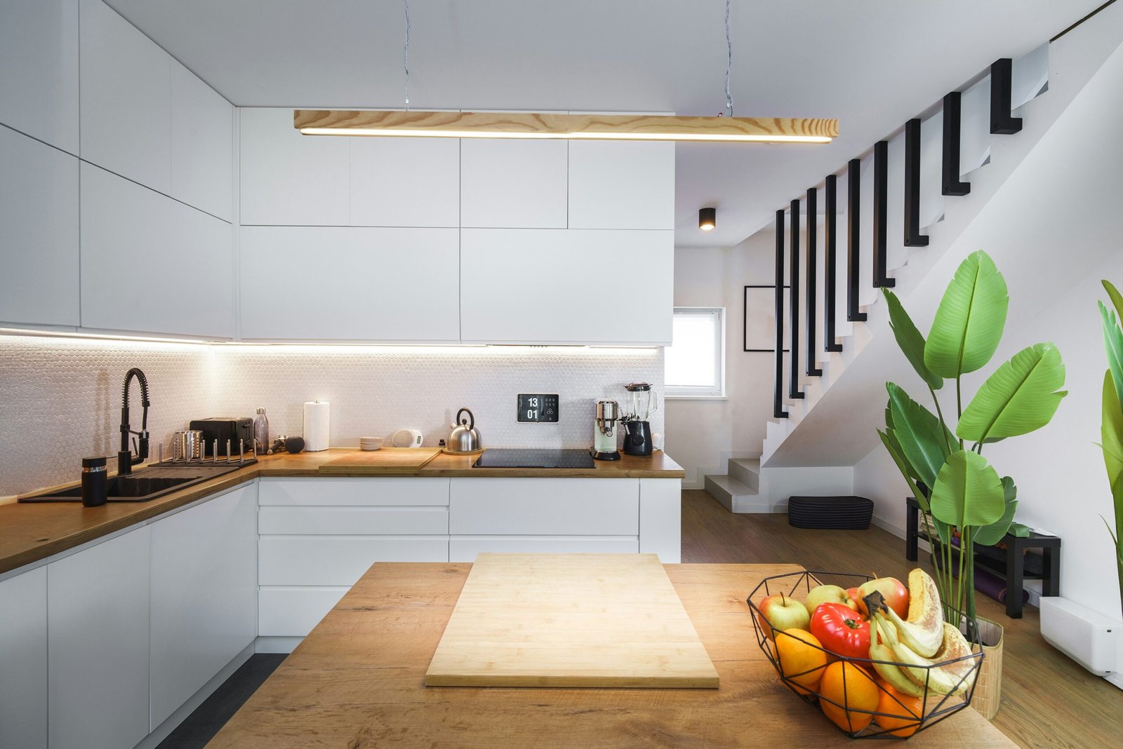 Cozinha moderna com escadas e planta decorativa.